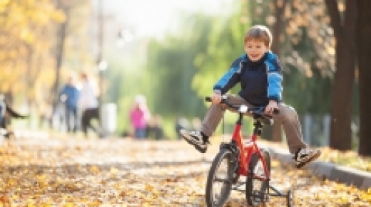 jongen fietst buiten over de herfstbladeren