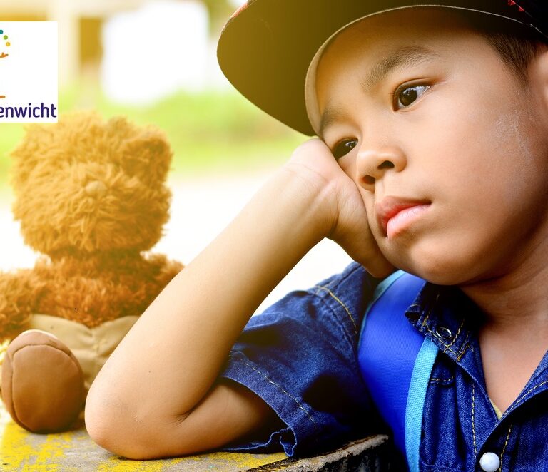 kind kijkt dromerig en zit naast zijn speelgoedbeer