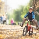 jongen fietst buiten over de herfstbladeren