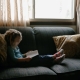 meisje leest zittend op de bank een boek